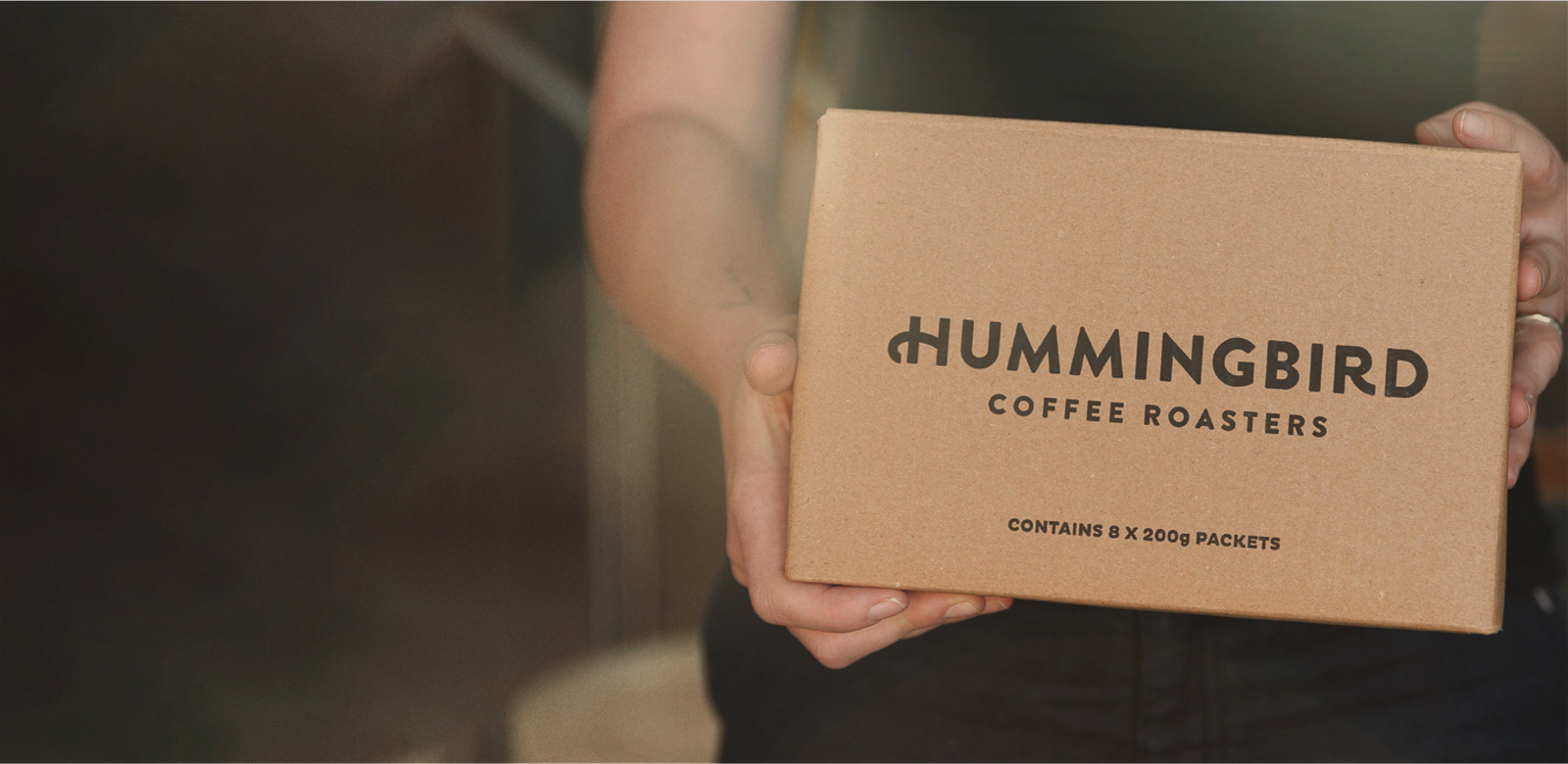 Hands holding a box of hummingbird coffee